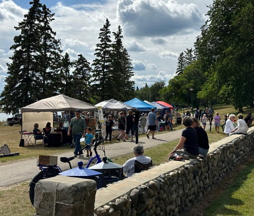 Dozens of visitors explore artists? work outside on a summer day.