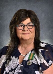 Valerie Bidaux, with brown hair and glasses, a Saskatchewan Volunteer Medal is pinned to her blouse. 