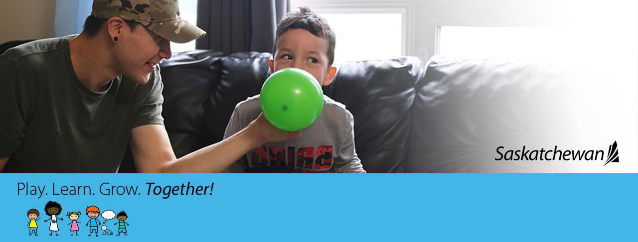 father helping son blow up a balloon