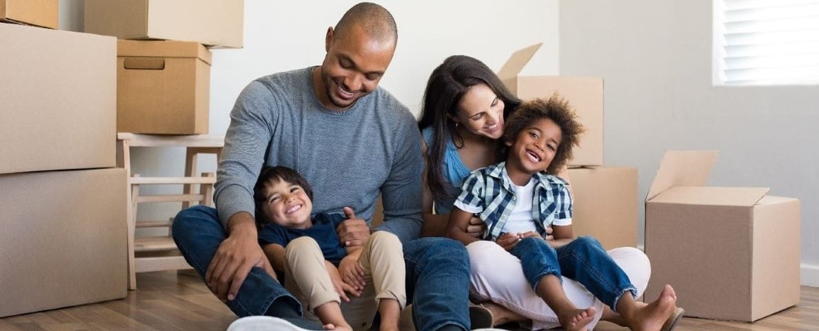 Happy family sitting on the floor surrounded by moving boxes