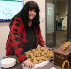 Lana Eering at a table with coffee and a tray of cookies.
