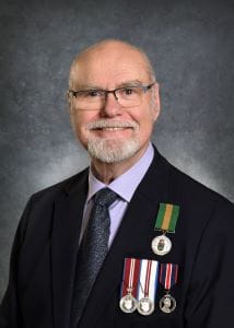 Harvey Linnen, wearing a black suit jacket. The Saskatchewan Volunteer Medal is pinned to his jacket above three other medals. 