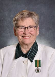 Sandy Lougheed wearing a white suit jacket with a dark collar, the Saskatchewan Volunteer Medal pinned to her jacket. 