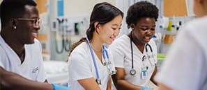 Group of nursing students smiling around a hospital bed