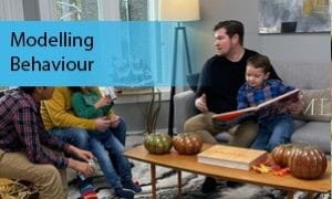 Two adults and three children sit together and read