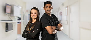 Two nurses back to back in a hallway.