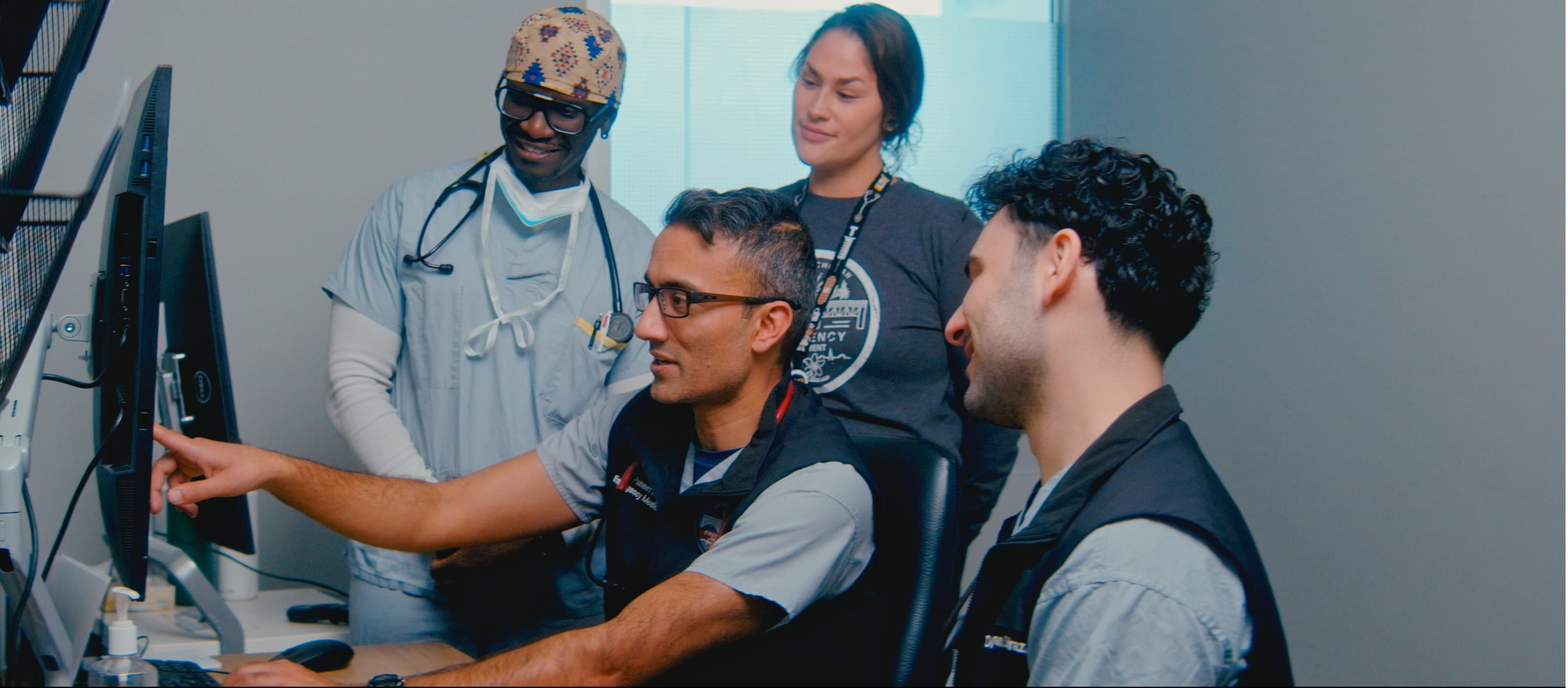 Group of four physicians looking at computer screen