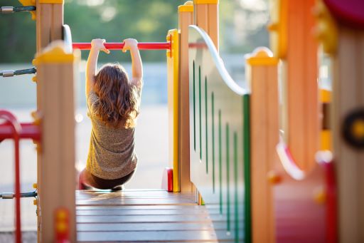long haired child going down a slide with text overlay "investing in school playgrounds, School Playground Equipment Grant program application period now open!