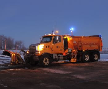 Snow plow on a highway at twilight
