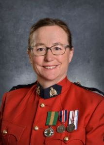 Laura Poppy, wearing a red RCMP jacket with the Saskatchewan Volunteer Medal pinned to it, next to two other medals. 