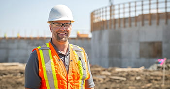 A man in a hard hat and reflective vest standing on a work site