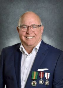 Rob Rongve, wearing a navy blue suit jacket and the Saskatchewan Volunteer Medal pinned to the left of two other medals. 