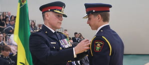 Prince Albert Police Service Chief Patrick Nogier places a badge on the uniform of a recent graduate at a Saskatchewan Police College graduation ceremony.