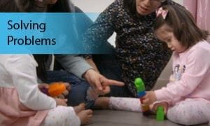 Two adults play with lego on the floor with two children