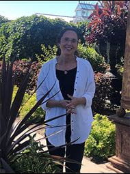 Debbie Sykora standing in front of greenery for a picture. 