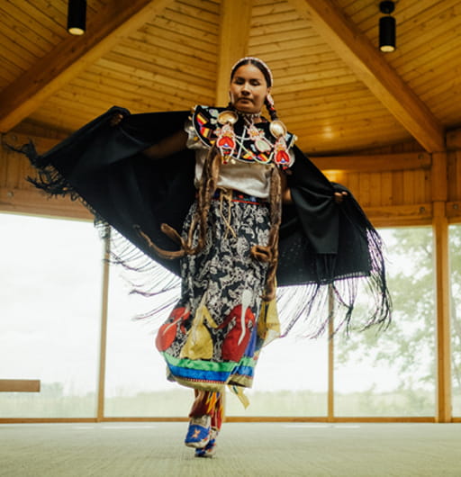 A woman, wearing traditional Indigenous regalia, dances indoors. Wanuskewin Heritage Park is a finalist at the 2026 Indigenous Tourism Awards, which will be held in Edmonton on February 19, 2026.