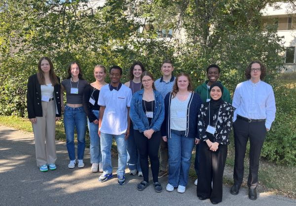 12 students stand together outside smiling. The students are the 2025-26 Ministry of Education Youth Council members.