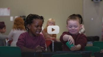 Two children are playing happily at a water table at the YMCA child care centre.