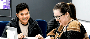 Happy people sitting at table looking at a computer.
