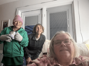 A woman posing for a selfie with two people smiling behind her.